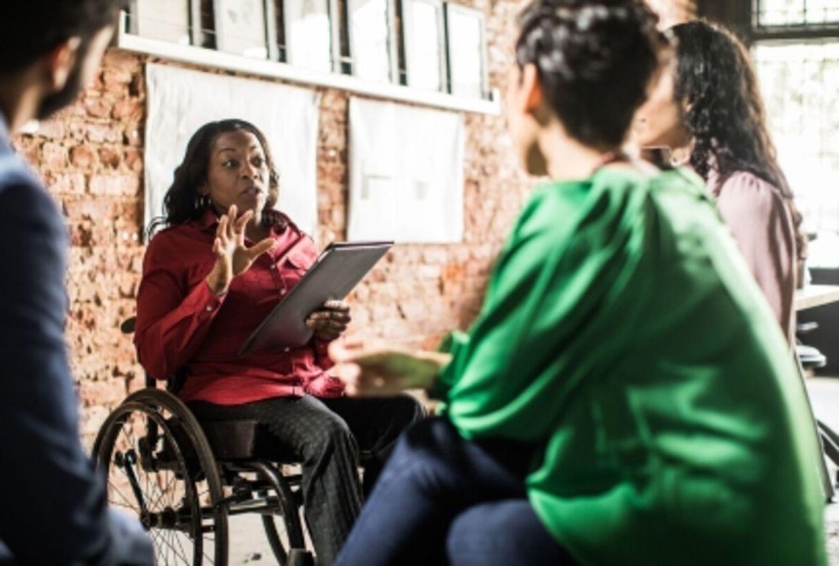 Businesswoman in wheelchair leading group discussion in creative office